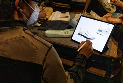 student designing sneakers on a tablet