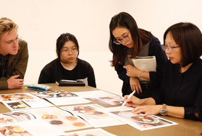 students and instructor looking at design work